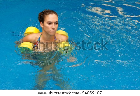 Woman in aqua aerobics with dumbbells. Water aerobic