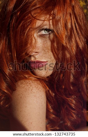Beautiful woman with red hair and freckles outdoors