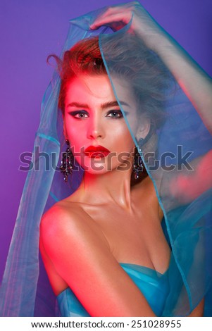 Fashion beauty model with evening art make up and hair, red light, color background. Studio shot. Blonde.