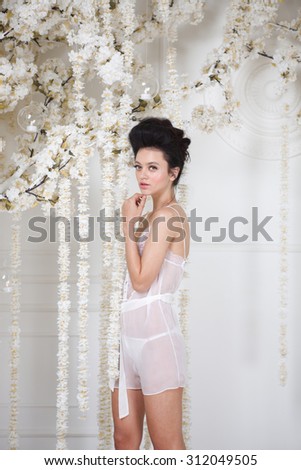 Portrait of a beautiful fashion girl in lingerie, sweet and sensual. Wedding make up and hair. Flowers background. Art modern style. Blue eyes