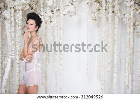 Portrait of a beautiful fashion girl in lingerie, sweet and sensual. Wedding make up and hair. Flowers background. Art modern style. Blue eyes
