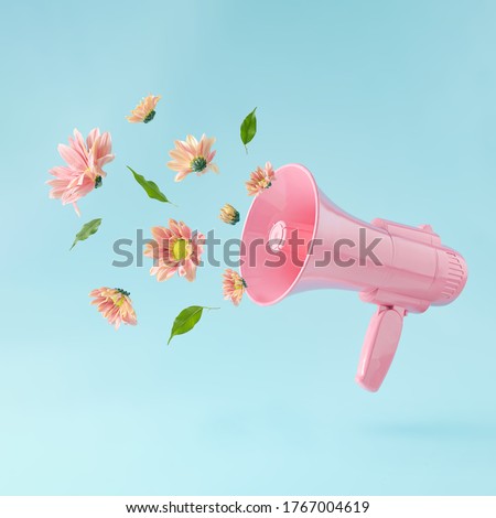 Pink megaphone with colorful summer flowers and green leaves against pastel blue background. Advertisement idea. Minimal nature concept.