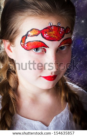 Pretty girl with face painting of sign of the zodiac Cancer