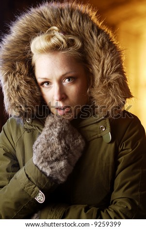 Woman in hood, backlit by warm light.