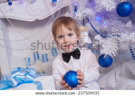 boy five years in anticipation of a gift, sitting near the Christmas tree, holding a blue balloon