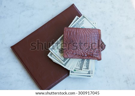 tablet on the table in a leather pouch and a leather purse with money