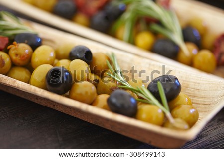 black and green olives, herbs, sun-dried tomatoes in an oblong dish
