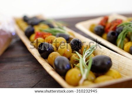 black and green olives, herbs, sun-dried tomatoes in an oblong dish