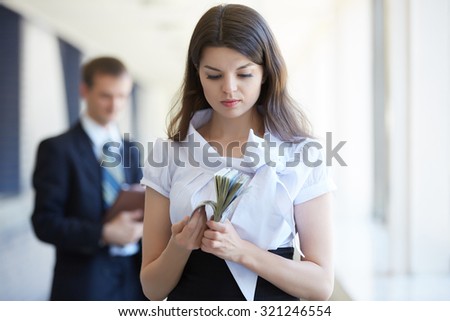 Business woman counts the money, businessman stands with tablet