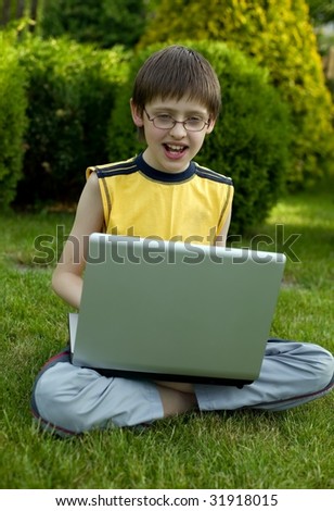 Boy with gray laptop computer in the garden