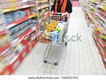 woman is moving shopping cart, the supermarket is motion-blurred