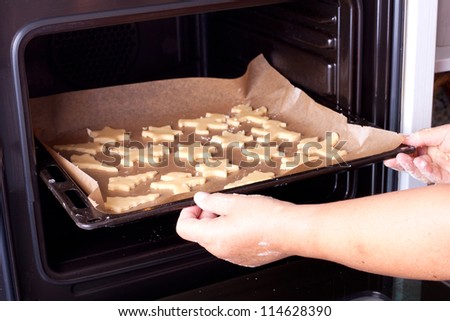 christmas cookies on a baking tray, woman is baking christmas cookies