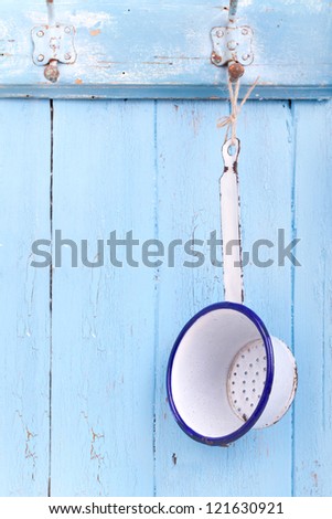 Rack of kitchen utensils on blue wooden rustic kitchen wall;