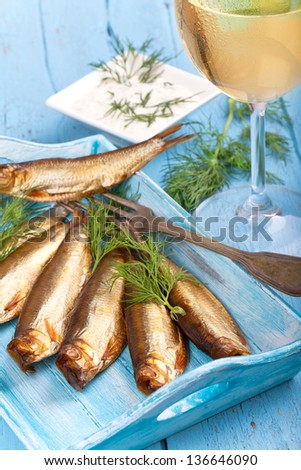 fresh smoked fish on a blue tray with fresh herbs - dill and a glass of white wine