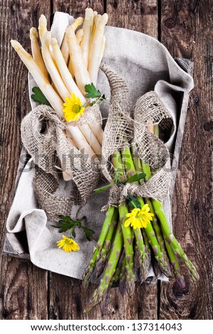 Fresh green and white asparagus bunch in a rustic basket on wooden table, bird\'s-eye view