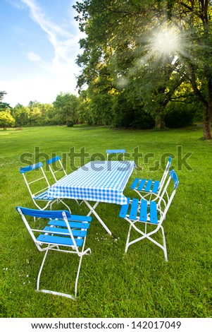 a table and some empty chairs on a green meadow in summer, ready for picnic