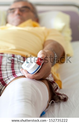 Knee surgery after operation patient senior man on the bed in Hospital, room at hospital with Equipment, man`s Hand is pressing emergency nurse call button