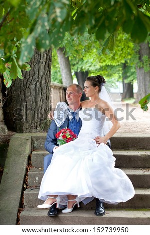bride and groom sit on stairs in garden and enjoying their wedding day