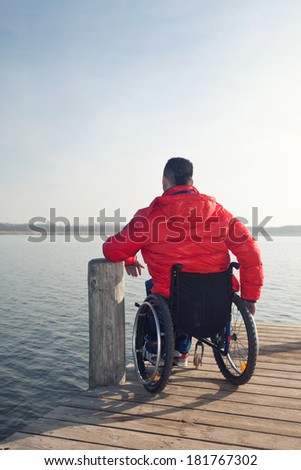 Handicapped man sits disabled in her wheelchair at the lake