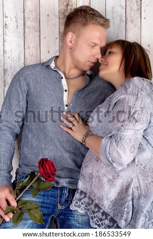 attractive couple in love in the pregnancy with a red rose as symbol of love and togetherness