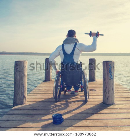 young man in wheelchair outside in nature, dumbbell training for fitness
