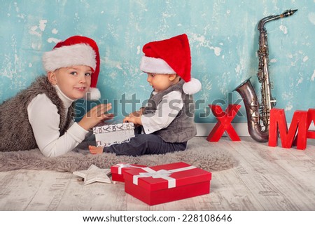 Kids in red santa hat with their christmas presents presents sitting and lying on the floor with Christmas decoration