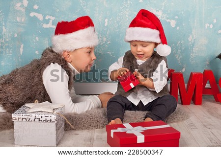 Kids in red santa hat with their christmas presents presents sitting and lying on the floor