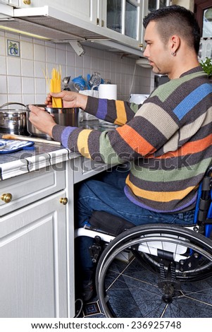 Young handicapped man in wheelchair works in his kitchen