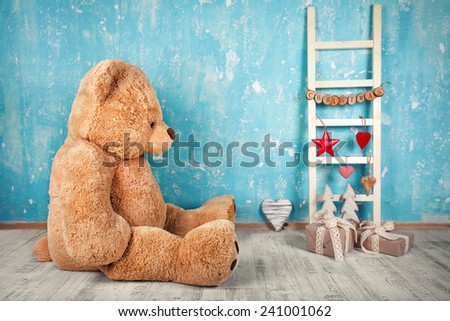 Christmas decoration on blue rustic wall, with ladder, gifts and bear
