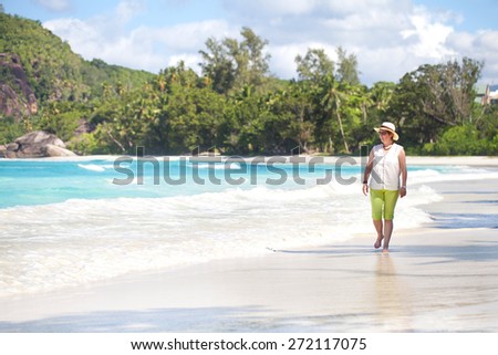 woman in casual clothing walk by the sea, seychelles beach