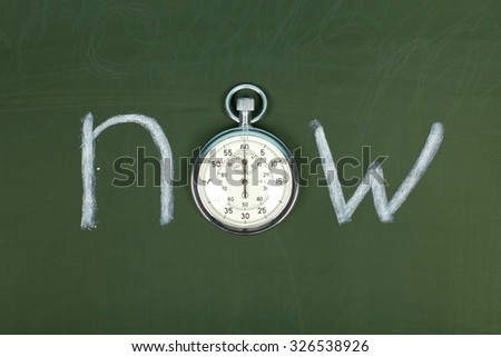 now - word handwritten on chalkboard with vintage precise stopwatch used instead of O