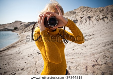 Foto Bild Junge blonde Hobby-Fotografin lächelt verschmitzt in die Kamera