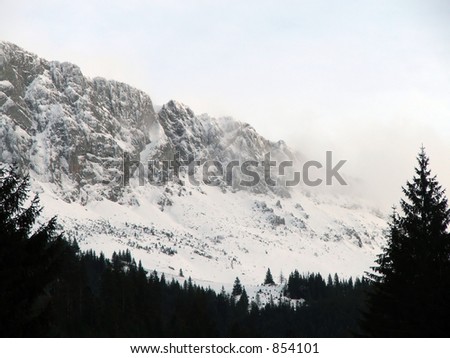 View of mountain peaks with forest dowhill and cloud covering the peaks