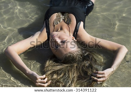 Girl wearing butterfly formed necklace lying in water half-body portrait