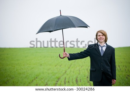 Smiling businessman holding umbrella - protection concept