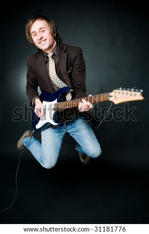 Jumping man with electro guitar, studio shot