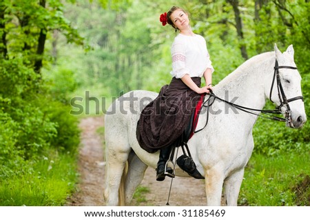 Cheerful girl riding horse in the forest