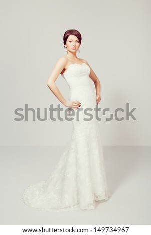Beautiful brunette bride in wedding dress, in studio, looking at camera