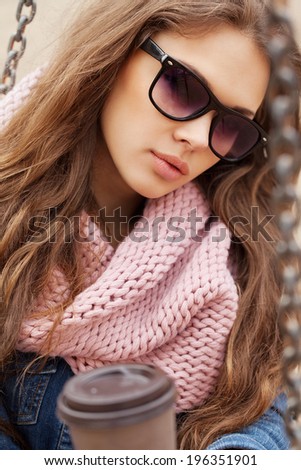 Close-up portrait of a beautiful brunette girl in sunglasses holding drink in her hands. Warm sunny day. Outdoors