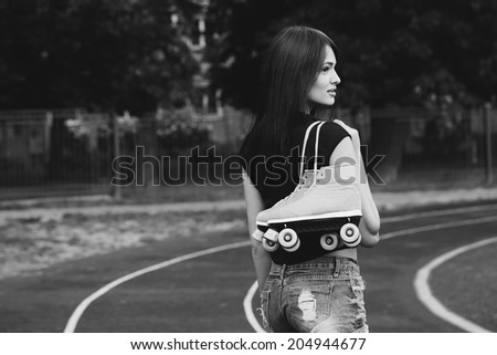 Portrait of a beautiful girl with roller skates on her shoulder walking down the street