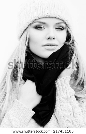 Portrait of a beautiful blonde girl wearing knitted beanie and wrapping up in a scarf.