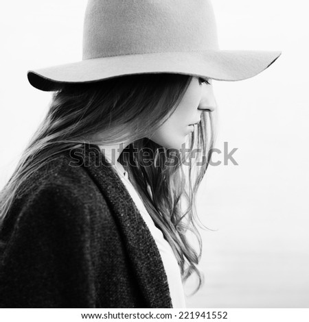 Closeup portrait of a pretty girl walking down lakeside. Profile to camera. Wearing hat and jacket. Outside