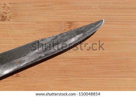 knife sits on a worn butcher block counter top