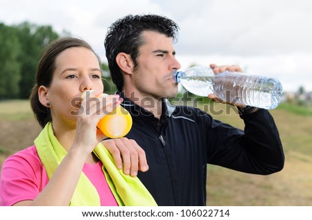 Sport couple drinking water and isotonic drink after training together. Young athletes.