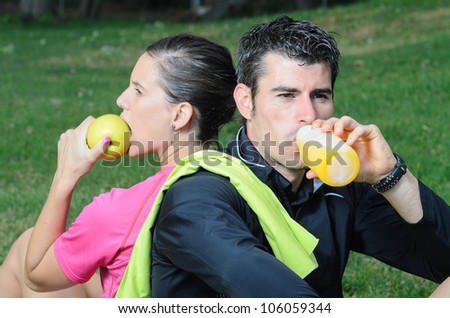 Athletes couple eating and drinking. Sport people taking a break.