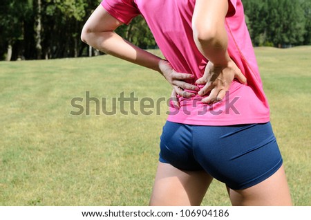 Back pain athlete. Sportswoman backache and injury. Female young runner with sports muscle injury.