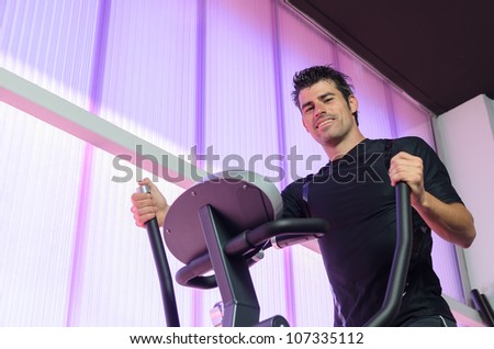 Male athlete exercising in elliptical treadmill machine. Man in gym training and burning fat. Handsome caucasian sportsman.