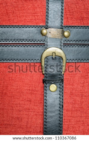 Old trunk leather closure. Black leather straps and metal golden buckle. Background.