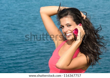 Close up of beautiful woman face talking by cell phone and smiling on blue sea background in summer