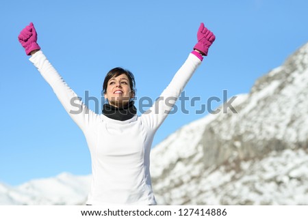 Fitness girl athlete success sport concept on winter road mountain background. Happy beautiful cheerful caucasian female athlete with arms up.